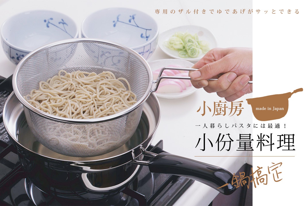 不鏽鋼網篩裝滿蕎麥麵，置於一個黑色的鍋子中，鍋內有水。背景有兩個藍白花紋的碗，以及裝有蔥段和魚板的小盤。