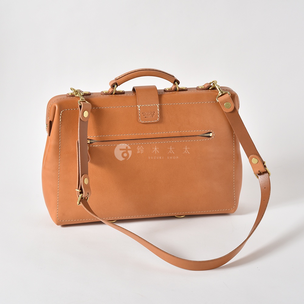 職人手作皮革軟式杜勒斯三用背包，呈現原色皮革質感，設有頂部提把、可拆卸肩帶、前方拉鍊暗袋及金屬扣環，風格經典。