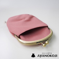 一個粉紅色帆布材質的口金包，採用古銅色金屬開合，包包上方有品牌 logo 和日文文字。