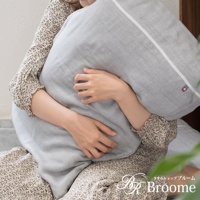 一位女士抱著一個淺灰色、五層紗質地的枕頭。枕套上有白色滾邊和一個帶有紅藍色標誌的小方塊。