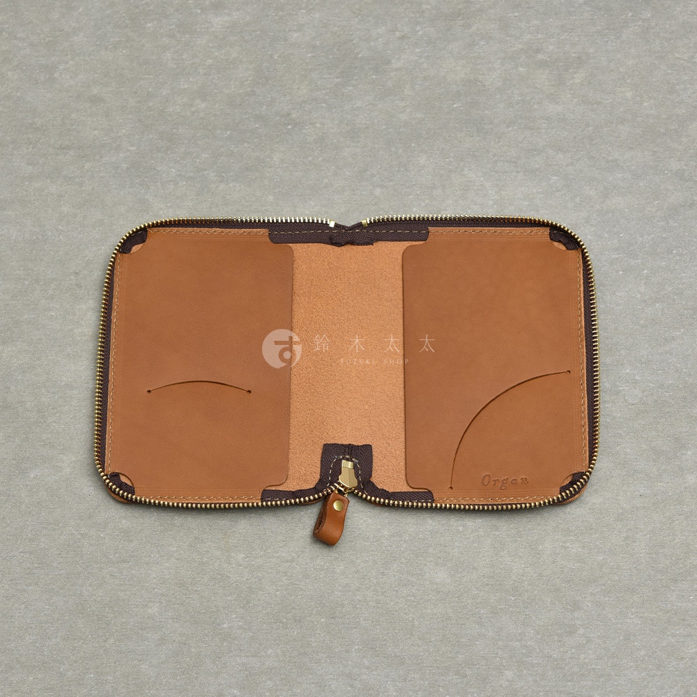 職人手作皮革Organ記事本收納包，打開的狀態，呈現棕褐色的皮革內裡，有兩個卡片夾層，中間有拉鍊開合。