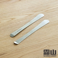 兩支銀色 304 不鏽鋼長柄包餡勺/抹刀，呈對角線排列於木紋背景上。其中一支勺柄上印有「SHIMOYAMA S304」字樣。