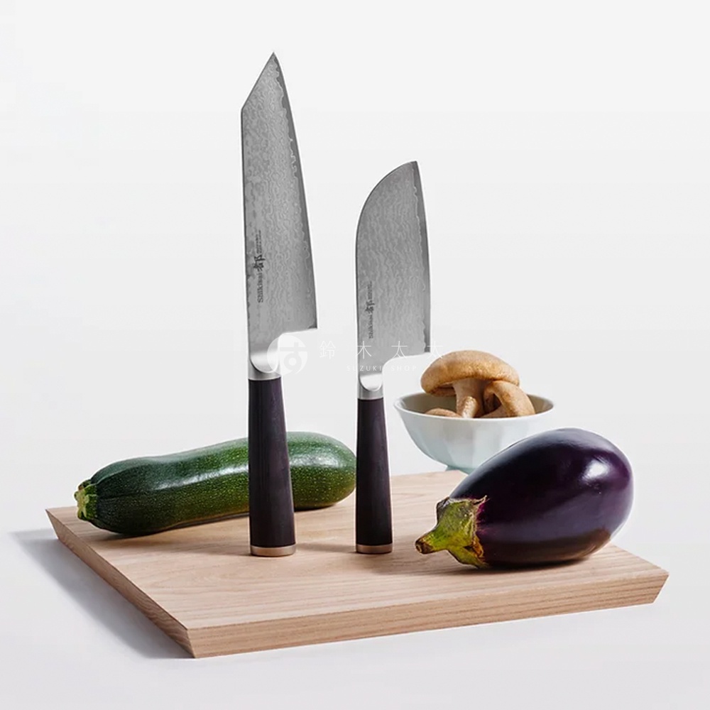 兩把都 / Bunka 文化刀，刀刃有細緻紋路，配深色木質手柄，置於木製砧板上，旁有櫛瓜、茄子及一碗香菇。