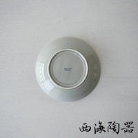 一個淺灰色、圓形、陶瓷材質的盤子，底部朝上，中央有藍色「Hasami Made in Japan」字樣。