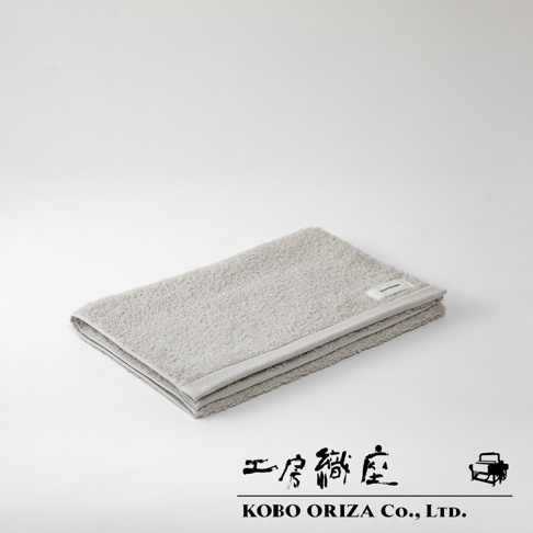 折疊的灰色超細纖維毛巾，觸感柔軟，邊緣縫線清晰，帶有品牌標籤。