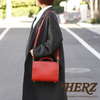 職人手作皮革兩用方形單肩包，採用紅色皮革製成，包身帶有手提把和可拆卸的肩帶，搭配金色金屬扣環。