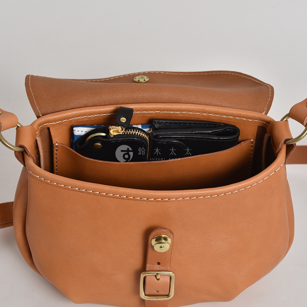 日本HERZ職人手作皮革休閒旅行馬鞍包，打開的包包內有錢包、零錢包和鑰匙，錢包上有日文「鈴木太太」字樣。
