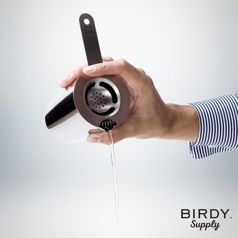 手持不鏽鋼濾酒隔冰匙，短柄設計，銀色金屬材質，濾網孔洞細緻，正用於過濾液體。