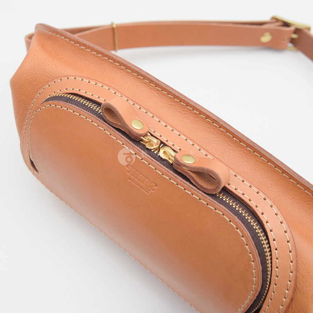 日本HERZ職人手作皮革拉鍊旅行斜背包，特寫金色拉鍊及品牌壓印，採用棕色皮革材質。