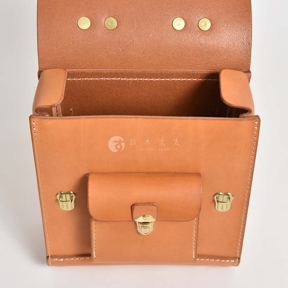 淺棕色皮革迷你後背包，學院風格設計，配有翻蓋、金屬釦、側邊釦和精細縫線。