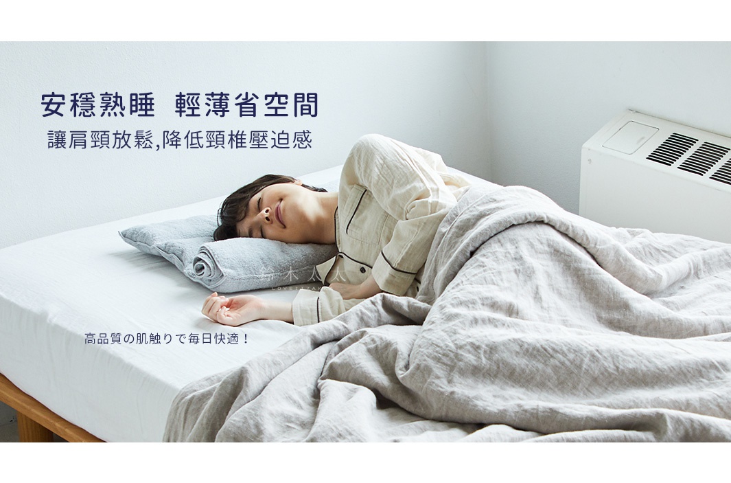 一位女士躺在床上，頭枕著一個淺灰色、捲起來的毛巾枕，枕頭由今治毛巾製成，質地柔軟，覆蓋著米白色亞麻被。