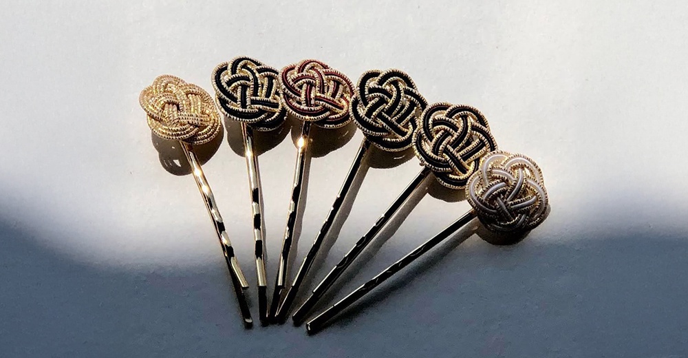 一排和風水引花結金絲髮夾，髮夾頂部飾有以金線與黑色、白色、紅褐色線條編織而成的立體花結，金屬髮簪呈現扭紋或光滑質地，整體散發日式典雅風格。