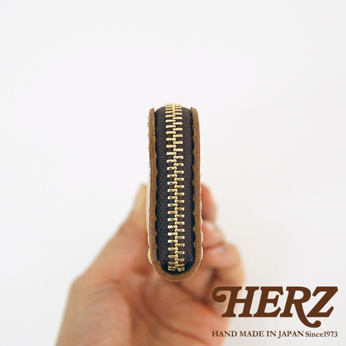 HERZ 品牌標誌，下方有 HAND MADE IN JAPAN Since1973 字樣，中間為一個棕色皮革拉鍊筆袋的側面特寫。