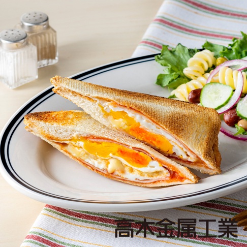 烤箱口袋吐司，內含煎蛋、火腿和融化起司，吐司外皮金黃酥脆，切面呈現豐富層次，搭配沙拉和調味罐。