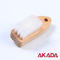 木製握柄的纖毛蔬果刷，刷毛為白色、柔軟的纖維材質，刷頭呈長方形，握柄一端有圓形掛孔。