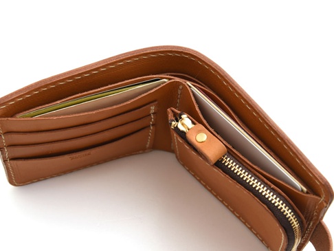 職人手作的棕色皮革短夾，內部有卡槽和拉鍊零錢袋，展示可拆式設計。
