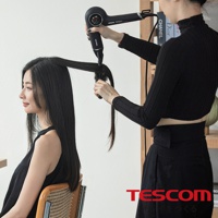 一位髮型師正在使用吹風機和梳子為一位女性吹乾頭髮，品牌 TESCOM 標誌在右下角