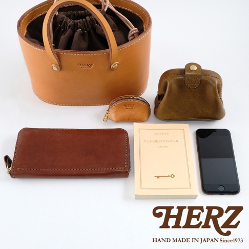 皮革束口手提包、咖啡色零錢包、棕色長夾、一本日文書籍及一支黑色手機，皆為皮革材質。