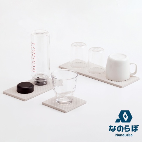淺灰色珪藻土置物墊，表面有細緻的條紋，上面擺放著一個透明水瓶（瓶身有紅色LONDON字樣）、一個黑色瓶蓋、兩個透明玻璃杯、一個有紋路的透明水杯，以及一個白色馬克杯。