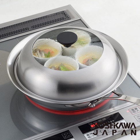 不鏽鋼蒸鍋盤，搭配透明玻璃鍋蓋，內有四個蒸杯，蒸煮著食材，置於電磁爐上，盤身呈現銀色金屬光澤。