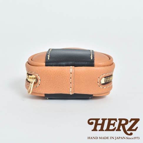 職人手作皮革三角飯糰造型小物收納包，咖啡色皮革搭配黑色皮革飾帶，設有金色拉鍊。