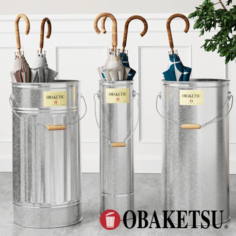 OBAKETSU 手工製傘桶，展示了不同尺寸的鍍鋅金屬傘桶，頂部裝有木柄傘，傘上有 OBAKETSU 品牌標籤。