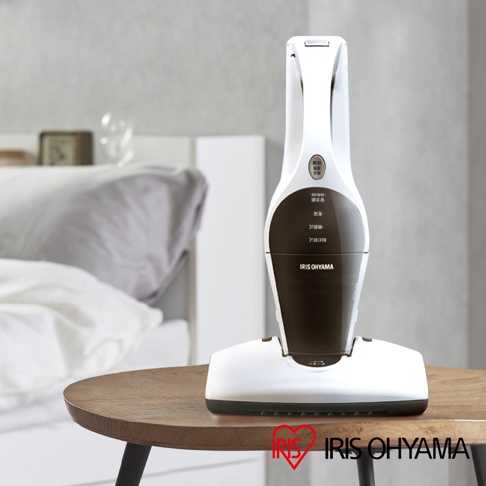 IRIS OHYAMA 充電式塵蟎機 IC-FDC-1T 放置在木製圓桌上，背景是臥室場景