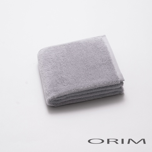 一張疊好的淺灰色毛巾，材質為柔軟的毛圈織物，邊緣有細緻的織紋。