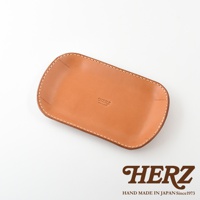職人手作皮革小物收納盤 KZ-1，採用天然皮革製作，呈現溫潤的淺棕色。盤身邊緣以白色車線縫製，整體線條簡潔，品牌標誌「HERZ」壓印於盤面中央。