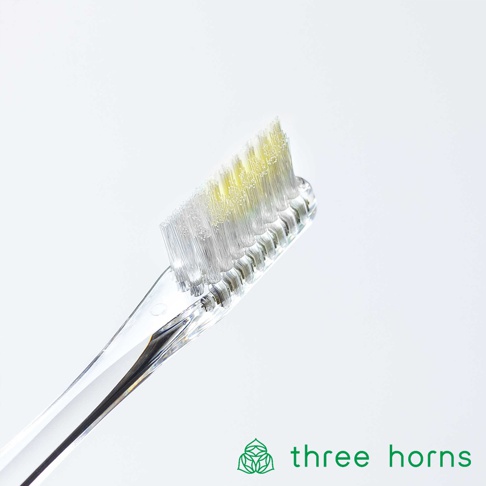 透明塑膠手柄的尖頭牙刷，刷毛為白色，部分帶有淡黃色，刷毛末端有細緻的清潔設計，整體乾淨簡約。