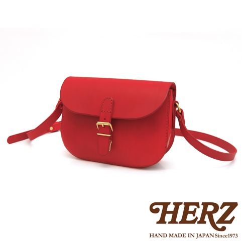 紅色皮革經典馬鞍包，配有金色搭扣和可調式肩帶，整體呈半圓形，簡潔大方。