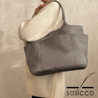 一位女士身穿米白色針織衫，肩背一個黑色與白色格紋圖案的刺子織手提托特包。