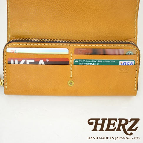 職人手作皮革長夾，呈現深棕色調，寬口設計方便拿取物品。內有卡槽，可放置多張信用卡與證件。拉鍊開合，材質為真皮。