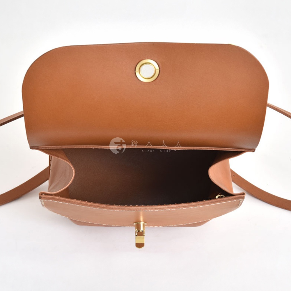 職人手作皮革翻蓋迷你後背包，採用溫暖的棕褐色皮革，配有金色金屬釦和車縫線細節，展現簡約的設計風格。