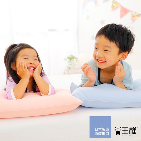 粉色及淺藍色枕頭，兩名兒童趴臥其中，枕頭表面為細緻織紋，材質應為柔軟布料。