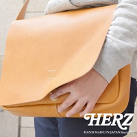 日本 HERZ 職人手作軟皮橫式斜背包，以淺棕色皮革製成，包面上繡有白色字母 Z，下方有金色旋釦，包身縫線細緻，整體散發職人手作質感。