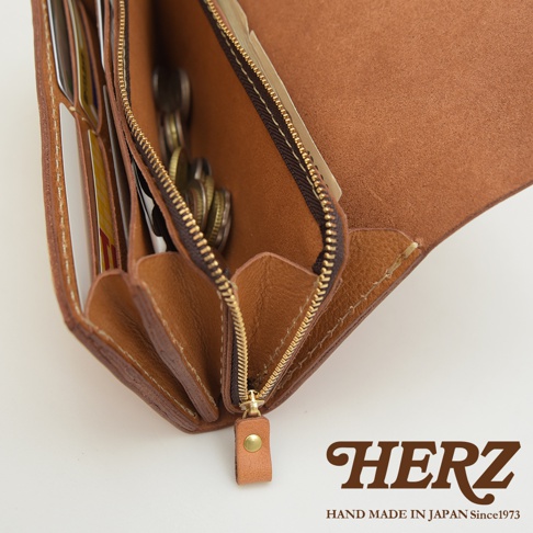 職人手作皮革長夾，展現自然皮革紋理，設有多個卡片夾層與拉鍊零錢袋，包含多枚硬幣，呈現多功能收納設計。