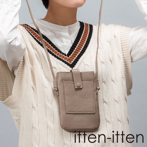 itten-itten 品牌 BOLLA 義大利皮革散步手機包，灰褐色荔枝紋皮革材質，設有鈕扣式翻蓋主袋及外插袋，搭配針織背心與白襯衫的穿搭。