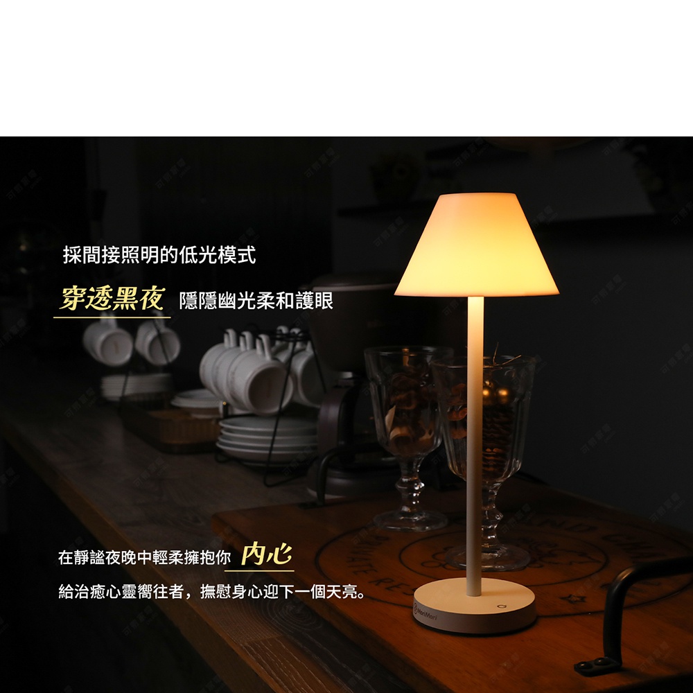 LED T-Light CAFE XL 傘型高版造型燈，燈罩為奶白色傘形，燈柱與底座為淺木紋色，散發溫暖黃光，置於木質桌面，背景為咖啡杯與酒杯。