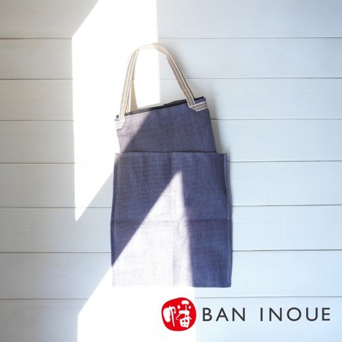 藍色蚊帳棉織隨身購物袋，織紋清晰，配有白色編織提把，袋面有條紋裝飾，整體簡約實用。