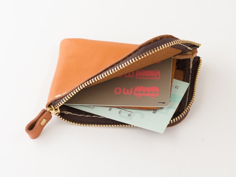 職人手作皮革迷你錢包，呈現自然的棕褐色皮革，搭配金色拉鍊。錢包內有卡片和票據，展示其分隔收納功能。