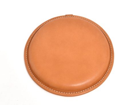 職人手作皮革圓形坐墊，淺棕色皮革，邊緣縫有白色縫線，圓形設計，簡約實用。
