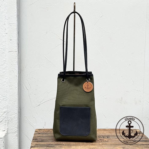 神戶clueto品牌軍綠色尼龍束口水桶包，配有義大利皮革前袋和船錨吊飾，適合日常使用。