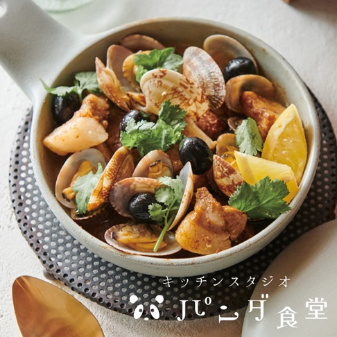 一鍋香濃的海鮮燉湯，裡面有蛤蜊、黑橄欖和香菜，旁邊點綴著幾片檸檬。