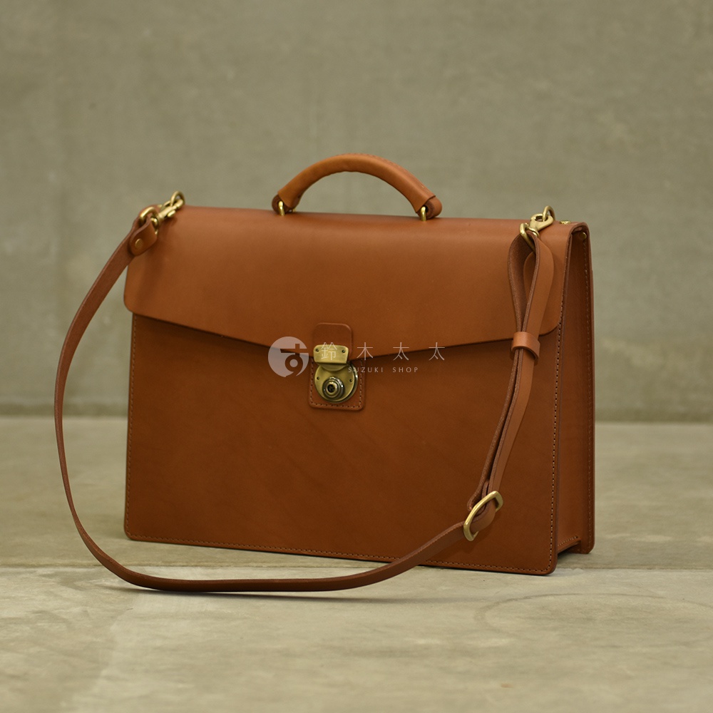 職人手作皮革Organ兩用商務公事包，採用棕色皮革製成，配有金屬旋轉鎖扣和可調節的皮革肩帶，具備手提與肩背功能。