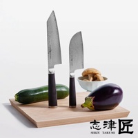 兩把都 / Bunka 文化刀，刀刃呈銀色，帶有 Damascus 紋理，手柄為深棕色。旁邊擺放著一根綠色櫛瓜、一顆紫色茄子、一小碗菇類，以及一個淺色木製砧板。