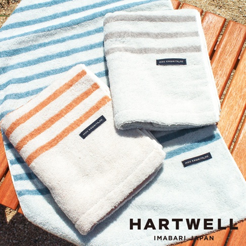三條今治迷你浴巾，分別為淡藍色條紋、米白色配橘色條紋、以及淺灰色條紋。皆為柔軟的棉質材質，帶有品牌標籤。