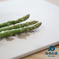 淺灰色條紋珪藻土置物墊上放著三支帶有水珠的綠色蘆筍。