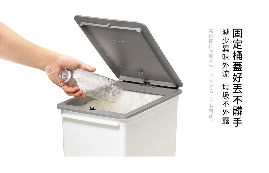 一只手正將一個透明塑膠瓶放入一個白色長方形垃圾桶。垃圾桶的蓋子是灰色的，已向上打開，露出內部裝有白色垃圾袋。