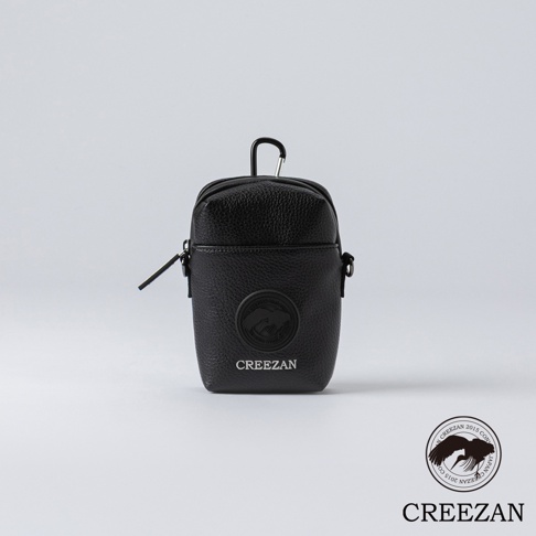 黑色皮革迷你側背包，帶有圓形品牌標誌和頂部掛鉤。